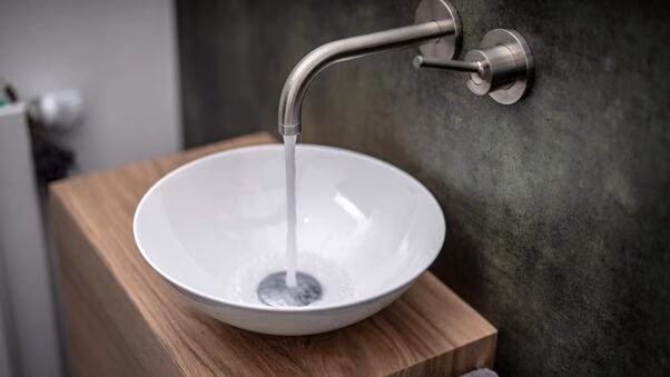 Wasser läuft aus einem Wasserhahn in ein modernes Waschbecken.