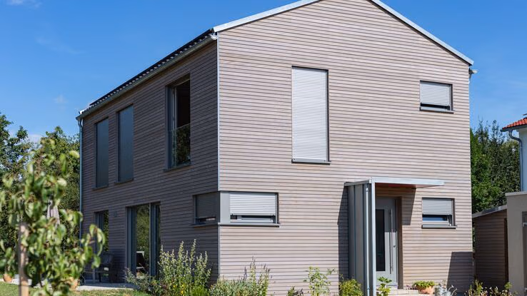 Es ist ein großes, modernes Haus mit Holzfassade abgebildet.